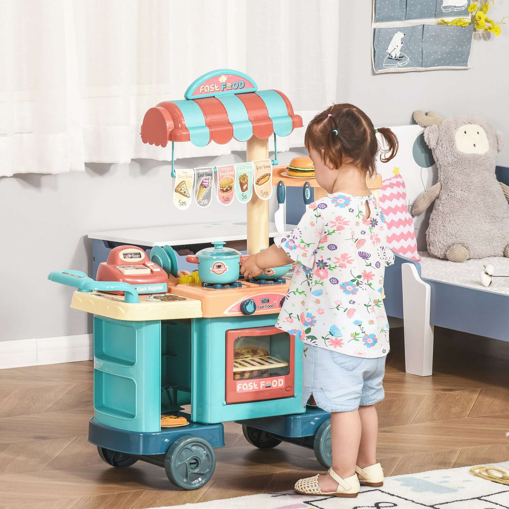 Child playing with a toy kitchen set in a room with a bed and stuffed animal.